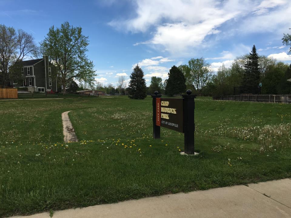 Sign reading Cleo Mudrock Park in a grassy field.
