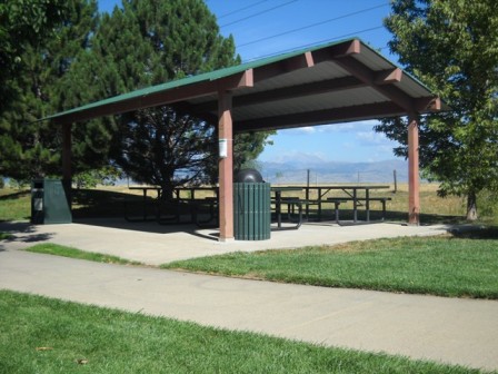 A shelter over a picnic table with trees in the background.